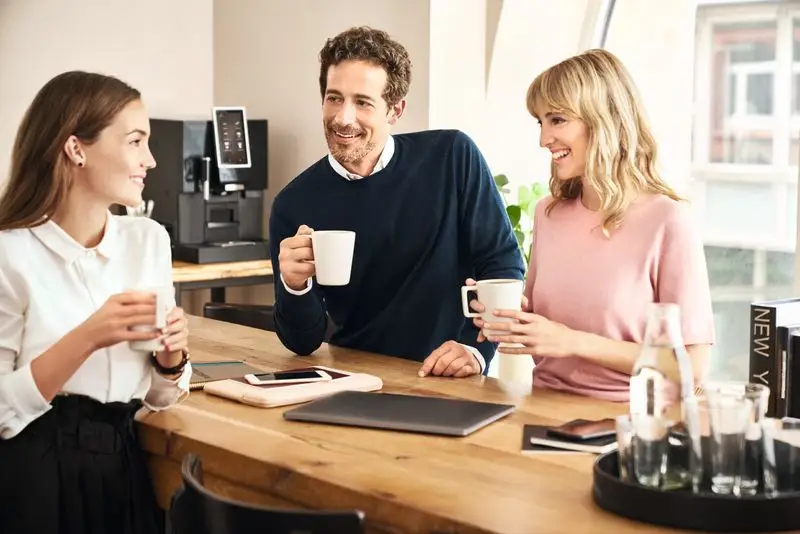 Coworkers brainstorming and enjoying coffee, wmf professional coffee machine on the background