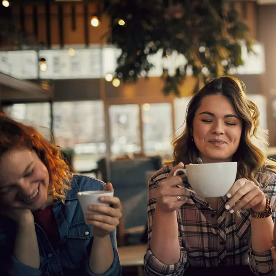 δυο γυναικες απολαμβανουν τον καφε τους σε μια καφετερια
